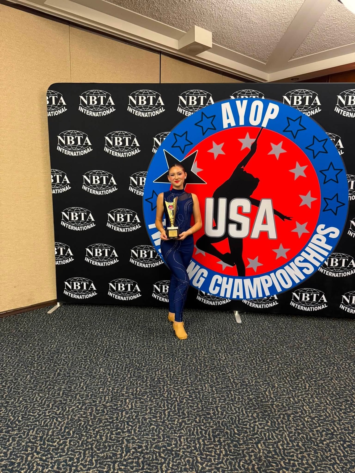 Captivators twirler with a championship trophy